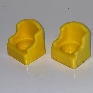 May include: Two yellow plastic chairs with a rounded back and a small seat. The chairs are designed for small children.
