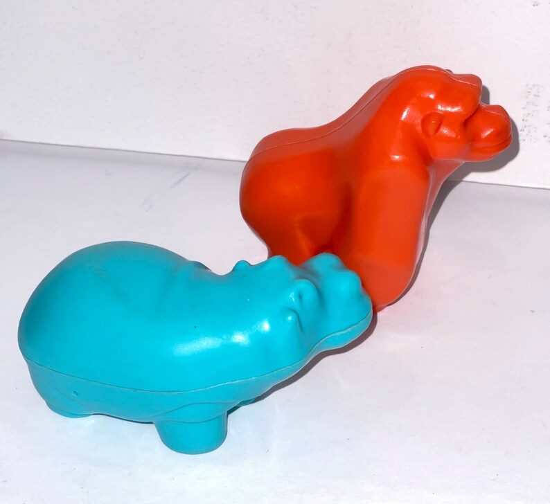 May include: A blue plastic hippopotamus toy and an orange plastic gorilla toy. Both toys are made of a smooth, shiny plastic.