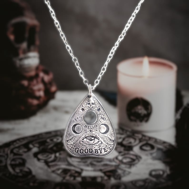 Silver necklace with a silver pendant shaped like a Ouija board planchette. The pendant has the words "Yes", "No", "Hello", "Goodbye" and an eye design.