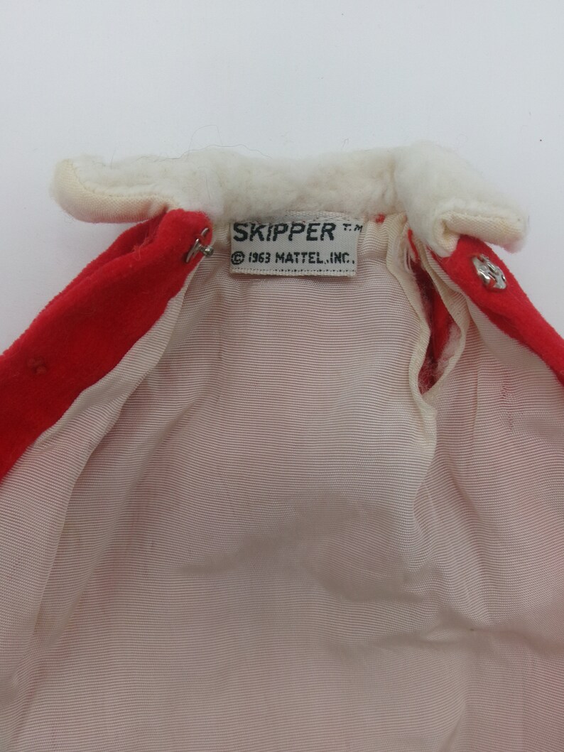 May include: Red and white doll coat with a white fur collar and a label that reads "SKIPPER T.M. &copy; 1963 MATTEL, INC."