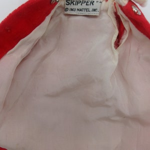 May include: Red and white doll coat with a white fur collar and a label that reads "SKIPPER T.M. &copy; 1963 MATTEL, INC."