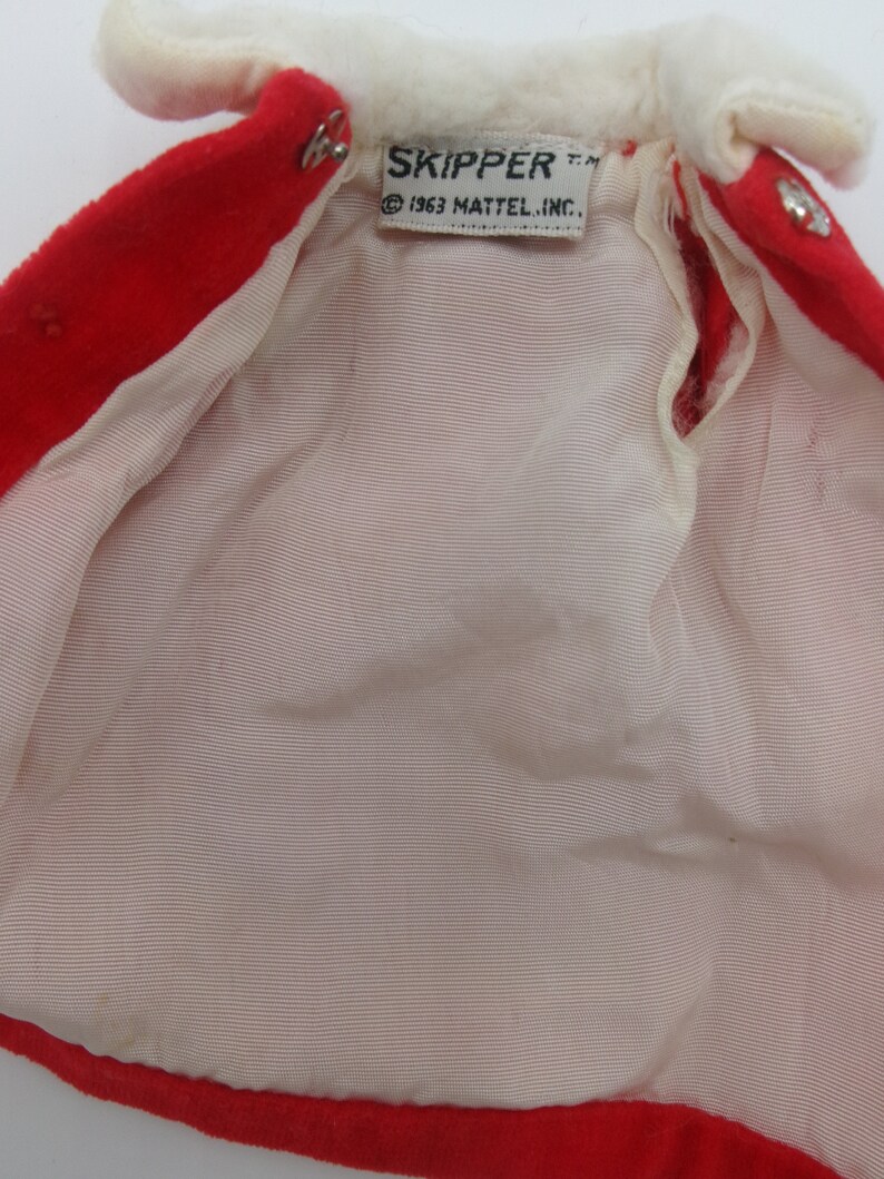 May include: Red and white doll coat with a white fur collar and a label that reads "SKIPPER T.M. &copy; 1963 MATTEL, INC."