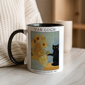 May include: White ceramic mug with a black handle and rim, featuring a print of Van Gogh's "Sunflowers" painting and a black cat. The mug includes the text "VAN GOGH" and "SUNFLOWERS (THIRD VERSION) - 1888".
