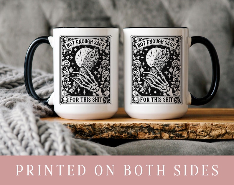 May include: Two white ceramic mugs with black handles and rims. Each mug features a black and white graphic with the text "NOT ENOUGH SAGE FOR THIS SHIT". The design includes a skeleton hand holding a bundle, a moon, and floral elements.