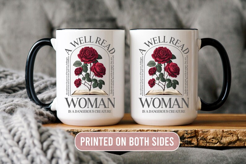 May include: Two white ceramic mugs with black handles and rims. Each mug features a design with red roses, an open book, and the text "A WELL READ WOMAN IS A DANGEROUS CREATURE". The phrase "PRINTED ON BOTH SIDES" is also visible.