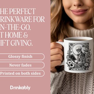 Puede incluir: Taza de cer&aacute;mica blanca con una ilustraci&oacute;n en blanco y negro de un esqueleto leyendo un libro, con el texto "THE READER". La taza tiene un acabado brillante y est&aacute; impresa por ambas caras. El texto a la izquierda dice "THE PERFECT DRINKWARE FOR ON-THE-GO, AT HOME & GIFT GIVING."