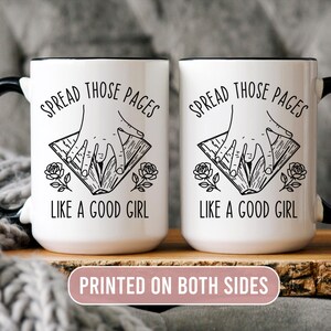May include: Two white ceramic mugs with black handles and rims. Each mug features the text "SPREAD THOSE PAGES LIKE A GOOD GIRL" in black, along with a hand illustration and floral accents. The mugs are printed on both sides.