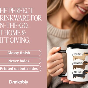 May include: White ceramic mug with a black handle and rim, featuring dachshund illustrations labeled "Light Roast," "Medium Roast," and "Dark Roast." The mug has the text "Drinkably" at the bottom and the words "THE PERFECT DRINKWARE FOR ON-THE-GO, AT HOME & GIFT GIVING."