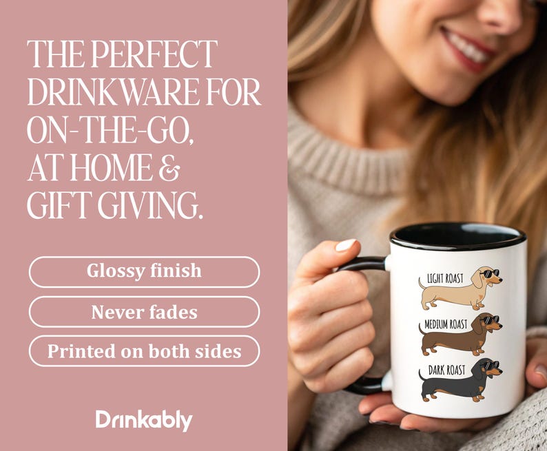 May include: White ceramic mug with a black handle and rim, featuring dachshund illustrations labeled "Light Roast," "Medium Roast," and "Dark Roast." The mug has the text "Drinkably" at the bottom and the words "THE PERFECT DRINKWARE FOR ON-THE-GO, AT HOME & GIFT GIVING."