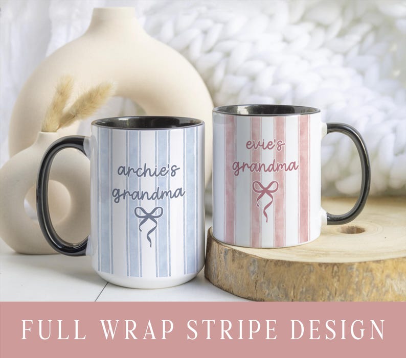 May include: Two ceramic mugs with black handles and rims. One mug has blue and white vertical stripes and the text "archie's grandma" with a bow graphic. The other mug has pink and white stripes and the text "evie's grandma" with a bow graphic. The mugs are on a wooden surface.