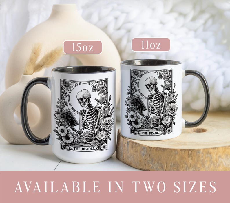 Puede incluir: Dos tazas de cer&aacute;mica blanca con asas y bordes negros. Cada taza presenta una ilustraci&oacute;n en blanco y negro de un esqueleto leyendo un libro, rodeado de elementos florales. El texto "THE READER" est&aacute; en la parte inferior. Disponibles en 312 ml y 425 ml.