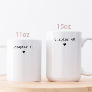 May include: Two white ceramic mugs with black text that reads "chapter 40" and a small black heart. The mugs are labeled "11oz" and "15oz". The image includes a small British flag in the upper left corner.