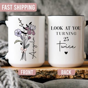 May include: A white ceramic mug with a black handle and rim. The front features a floral bouquet illustration with the name Angela. The back displays the black text LOOK AT YOU TURNING 25 twice with a small heart symbol below the lettering.