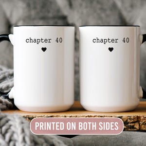 May include: Two white ceramic mugs with black handles and rims. Each mug has the text "chapter 40" above a black heart. The mugs are displayed on a wooden surface, with a gray knitted blanket in the background. The text "PRINTED ON BOTH SIDES" is also visible.