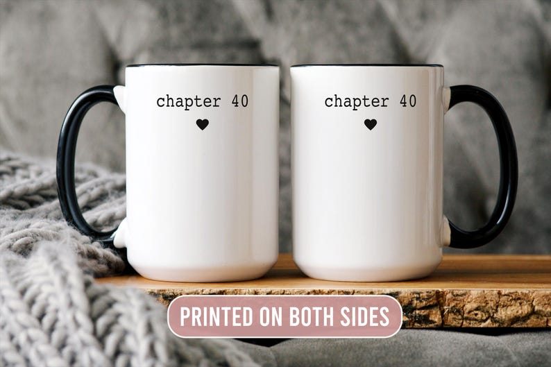 May include: Two white ceramic mugs with black handles and rims. Each mug has the text "chapter 40" above a black heart. The mugs are displayed on a wooden surface, with a gray knitted blanket in the background. The text "PRINTED ON BOTH SIDES" is also visible.