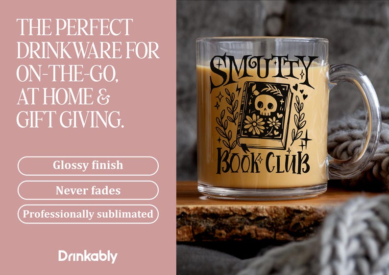 K&ouml;nnte beinhalten: Ein klarer Glasbecher mit Henkel, gef&uuml;llt mit einer hellbraunen Fl&uuml;ssigkeit. Der Becher hat schwarzen Text und eine Grafik eines Buches mit einem Totenkopf auf dem Cover, mit den Worten "SMUTTY BOOK CLUB".
