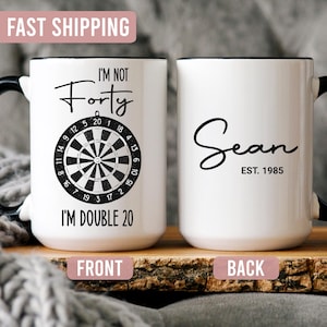 May include: White ceramic mug with black handle and rim. The front features a dartboard graphic and the text "I'M NOT Forty I'M DOUBLE 20". The back has the name "Sean" and "EST. 1985".