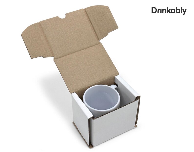 May include: A white ceramic mug inside a white cardboard box with a brown cardboard lid. The mug is centered in the box, and the lid is open. The text "Drinkably" is in the upper right corner.