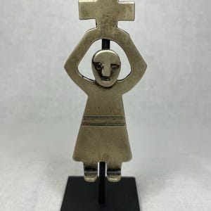 Puede incluir: Una taza de cerámica blanca con un asa negra y el texto "But First, Coffee" en negrita negra. La taza se encuentra sobre un fondo neutro, resaltando su diseño sencillo.