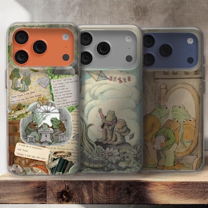 Puede incluir: Tres fundas para teléfono con ilustraciones de un libro infantil. Las fundas presentan imágenes de ranas, texto y una cometa. Las fundas están sobre una superficie de madera.