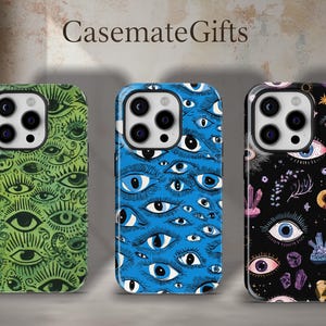 Peut inclure: Trois coques de téléphone avec des motifs d'yeux. L'une est verte avec des yeux noirs, une autre est bleue avec des yeux blancs, et la troisième est noire avec des yeux roses, violets et blancs. La marque "CasemateGifts" est en haut.