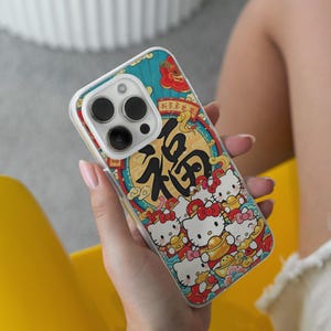 May include: A phone case with a vibrant design, including the Chinese character "福" in black, set within a gold circle and red details. The case also features cartoon cats. The case has a clear border.