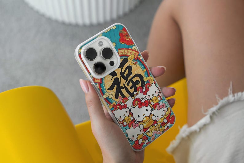 May include: A phone case with a vibrant design, including the Chinese character "福" in black, set within a gold circle and red details. The case also features cartoon cats. The case has a clear border.