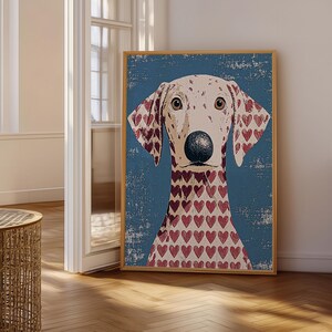 Könnte beinhalten: Ein gerahmter vertikaler Wandkunstdruck mit einem stilisierten Hundeporträt vor einem strukturierten blauen Hintergrund. Der Hund hat ein helles Fell mit einem wiederkehrenden Muster aus kleinen roten Herzen, einer großen dunklen Nase und braunen Augen.