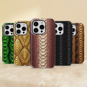 May include: A collection of five phone cases with various snake skin patterns. The cases feature a range of colors, including green, gold, brown, black, and tan. Each case has a camera cutout and a smooth, glossy finish.