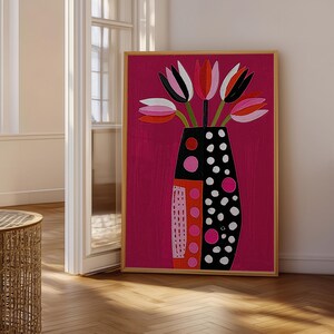 May include: A framed wall art print featuring a vibrant magenta background with a stylized vase containing tulips. The vase is black with white polka dots and a side panel of orange and pink circles. The tulips are pink, white, and black.