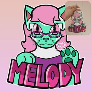 May include: A cartoon cat character with teal fur, pink hair, and glasses. The cat is wearing a purple shirt and has the name "MELODY" in large pink letters below. A smaller version of the character is shown as a keychain.