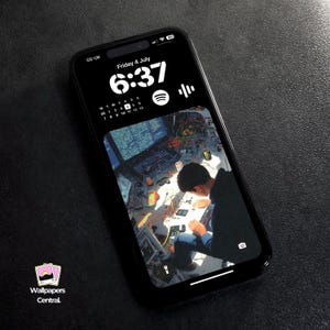 Peut inclure: Smartphone noir affichant un fond d'écran détaillé d'une personne travaillant sur de l'électronique. L'écran affiche l'heure, la date et l'icône Spotify. Le téléphone est sur une surface sombre. Le texte "Wallpapers Central" est visible.