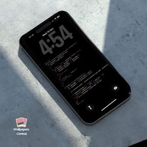 May include: A black smartphone displays a dark theme with code and the time 4:54. The screen shows lines of code in red and white text. The phone has a black border and is angled on a light gray surface. The logo "Wallpapers Central" is visible.