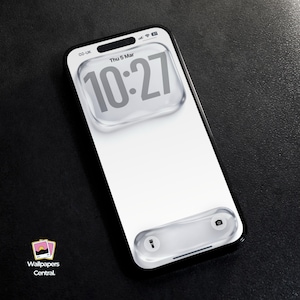 以下が含まれることがあります： 白い画面に時刻、日付、ロック画面インターフェースが表示されたスマートフォン。電話機は黒いフレームと光沢のある仕上げです。表示されている時刻は10:27です。電話機は黒い表面にあります。「Wallpapers Central」のロゴが左下にあります。