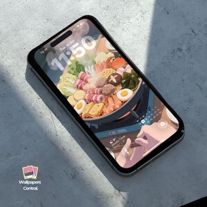 May include: A smartphone with a black case displays a colorful illustration of a hot pot with various ingredients. The screen shows the time as 11:50 and the date as Tuesday, October 14. The phone is on a gray surface, with the "Wallpapers Central" logo visible.