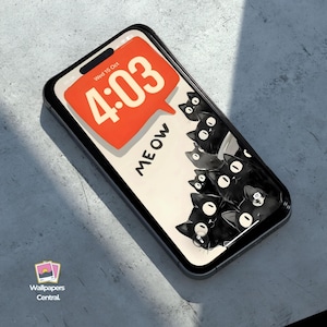 May include: A black smartphone with a screen displaying a cartoon design of black cats and the word "MEOW". The time 4:03 is shown in an orange speech bubble. The phone is on a gray surface.