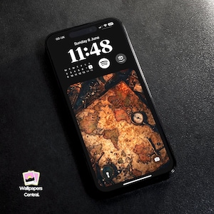May include: A black smartphone displays a vintage world map wallpaper with a compass and other navigational tools. The screen shows the time as 11:48 on Sunday, June 8th. The phone has the text "02-UK" and the logo for Wallpapers Central.