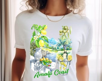 Op de afbeelding: Wit T-shirt met een aquarel illustratie van de Amalfikust. Het ontwerp bevat citroenen, olijven, een fles en de tekst "Amalfi Coast" in het groen. Het shirt heeft een klassieke ronde hals.