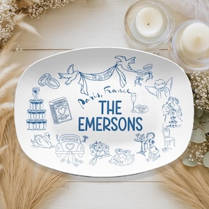 May include: White oval serving platter with blue line art illustrations of wedding icons. The platter features the text "Paris, France" and "THE EMERSONS" with the date "08.24.2025".