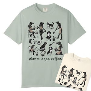 May include: Two light green t-shirts with a black silhouette design of women and dogs gardening. The text "plants. dogs. coffee." is printed on the front of the shirts.