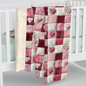 May include: A pink and red patchwork blanket with heart-shaped accents. The blanket features a variety of textures, including faux fur and plush squares. The blanket is draped over a white crib.