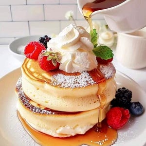 May include: A stack of fluffy pancakes topped with whipped cream, fresh berries, and powdered sugar. Syrup is being poured over the pancakes from a white pitcher. The pancakes are on a white plate, with a white background.