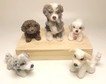 May include: Five miniature dog figurines in various breeds and colours, including brown, grey, and white. One dog wears a pink bow. The figurines are displayed on a wooden platform.