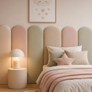 Può includere: Una camera da letto con testiera a parete composta da pannelli verticali imbottiti ad arco, che alternano tonalità verde salvia, rosa cipria e crema. Il letto è coperto da lenzuola bianche con una coperta rosa e un cuscino a forma di stella.