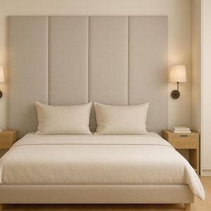 Può includere: Un letto imbottito beige con cuscini e biancheria da letto abbinati. La testiera presenta un design a pannelli verticali. Due comodini in legno con lampade affiancano il letto. Un grande armadio bianco è sulla destra.