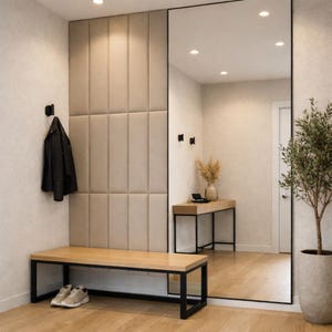 Puede incluir: Una entrada moderna con un espejo de cuerpo entero, un banco de madera con marco de metal negro y una chaqueta negra colgada en la pared. Las paredes son beige con un diseño de paneles acolchados.