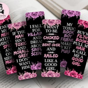 Könnte beinhalten: Eine Sammlung schwarzer Lesezeichen mit Zitaten in Weiß und Rosa, verziert mit rosa und lila Rosen. Die Lesezeichen sind auf einem offenen Buch angeordnet. Das Arbels-Logo befindet sich oben links.