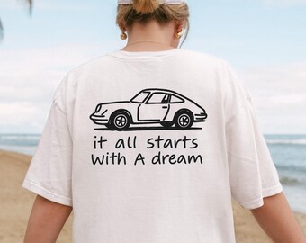 May include: White t-shirt with a black line drawing of a classic car and the text "it all starts with A dream." The shirt is a casual style, perfect for everyday wear.