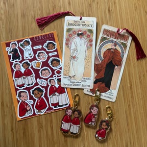 May include: A selection of religious-themed merchandise, including stickers, bookmarks, and keyrings. The stickers depict cartoon illustrations of religious figures. Bookmarks feature vintage art of religious figures. Keyrings show cartoon figures in red robes.
