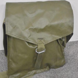 Puede incluir: Bolso mensajero verde oliva con cierre de solapa y correa de hombro ajustable. El bolso presenta una correa tejida con una hebilla de metal. El bolso está hecho de un material duradero y resistente al agua.